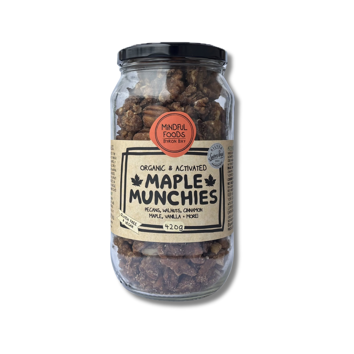 A glass jar of Mindful Foods Maple Munchies on a white background. The jar contains brown maple treats and has a black lid with a beige and orange label.