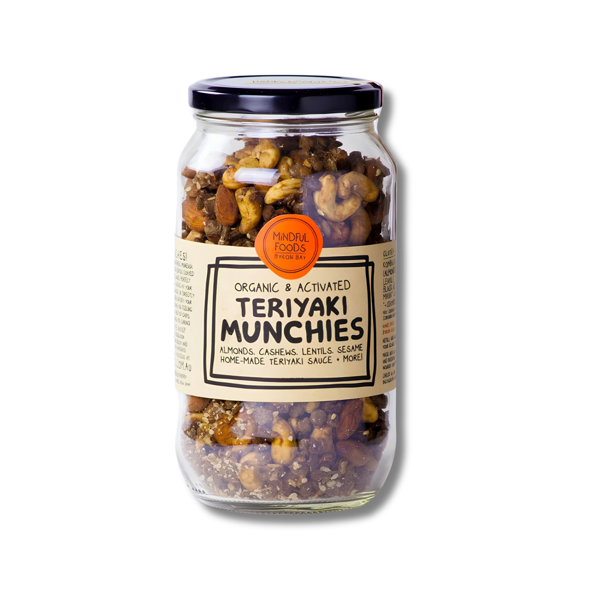 A glass jar of Mindful Foods Teriyaki Munchies, featuring a beige label with black text and an orange circular seal, filled with mixed nuts and dried fruit, set against a plain white background.