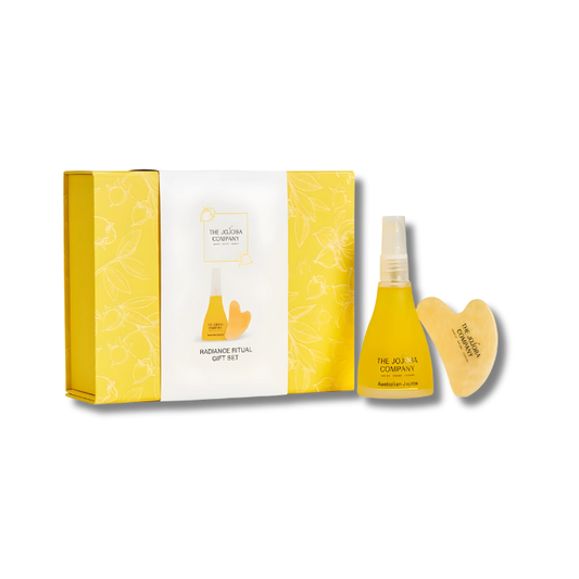 A skincare gift set featuring The Jojoba Company Australian Jojoba 85ml bottle and a smooth Gua Sha facial tool. Both items are beautifully displayed in soft, golden packaging on a neutral background, evoking calmness and natural radiance.