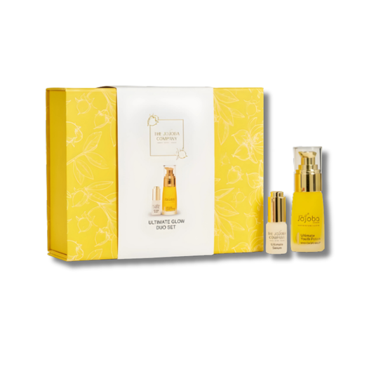 Two skincare bottles from The Jojoba Company Ultimate Glow Duo Set one 30ml Ultimate Youth Potion and one 7ml Ultimate Serum  elegantly displayed in gold and amber packaging. The set is styled on a soft, neutral background, highlighting its premium, luxurious, and radiant look.