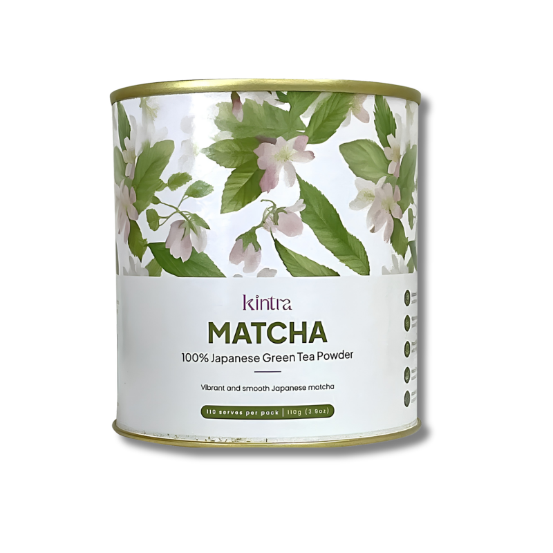 A cylindrical metal tin of Kintra Matcha 100% Japanese Green Tea Powder, featuring a white label with green leaves and pale pink blossoms, and a gold-colored rim, set against a plain white background.