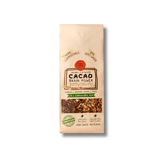 A package of Organic & Accurate Cacao Brain Power granola, featuring a beige paper bag with a clear window showing the mixed nuts and cacao pieces inside.
