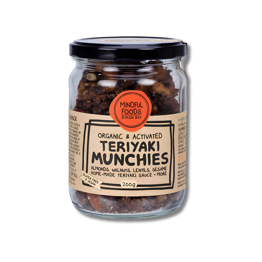 A glass jar of Mindful Foods Teriyaki Munchies, featuring a black lid and a beige label with a prominent orange circular logo, set against a plain white background.