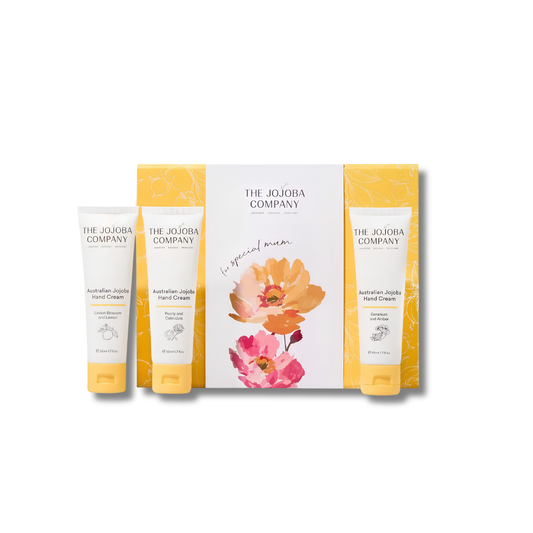 Three tubes of The Jojoba Company Australian Jujube Hand Cream arranged in front of a matching gift box on a white background. The packaging features a white and yellow floral design with orange and pink flowers.