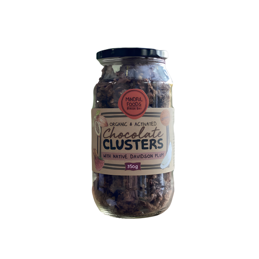 A glass jar of Minroll Foods Organic & Activated Chocolate Clusters with Native Davidson Plum, featuring a cream-colored label with red and black text, a black lid, and a white background.
