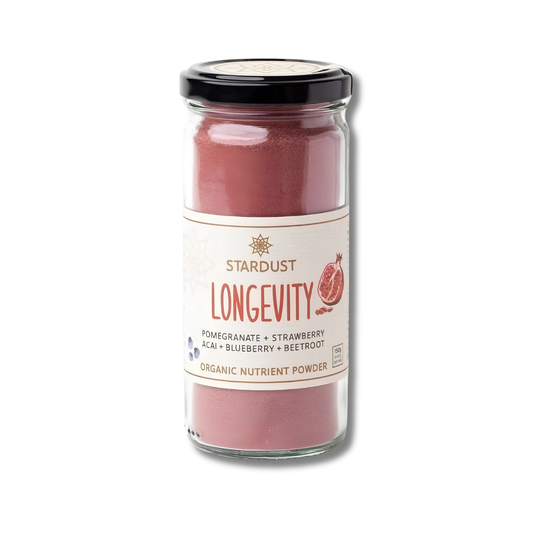 A glass jar of Stardust Longevity Organic Nutrient Powder, featuring a black lid and a cream-colored label with red and blue text, set against a plain white background.