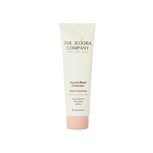 A 120ml squeeze tube of The Jojoba Company Jojoba Bead Cleanser on a solid white background. The tube is off-white with black text and a light pink cap.