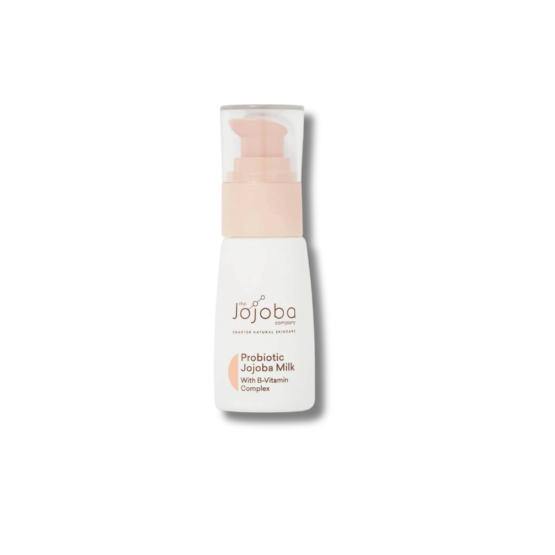 A bottle of Jojoba Beauty Probiotic Jojoba Milk with Vitamin Complex, featuring a white bottle, a light peach pump dispenser, and a clear cap, set against a plain white background with a soft shadow.